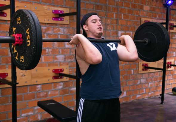 A man focuses on lifting a heavy barbell in a Ciudad de México gym.