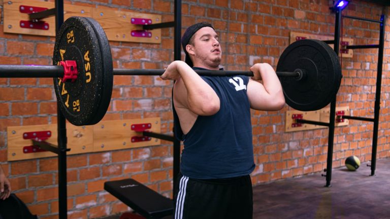 A man focuses on lifting a heavy barbell in a Ciudad de México gym.